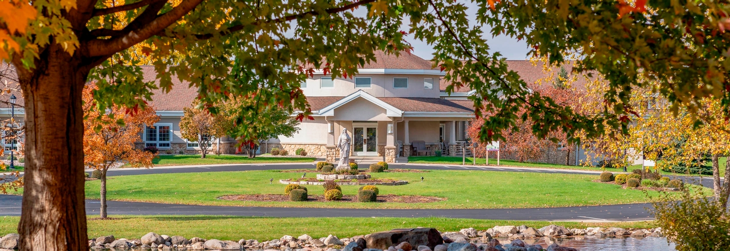 Image: a statue of St. Agnes outside the CSA motherhouse on a fall day